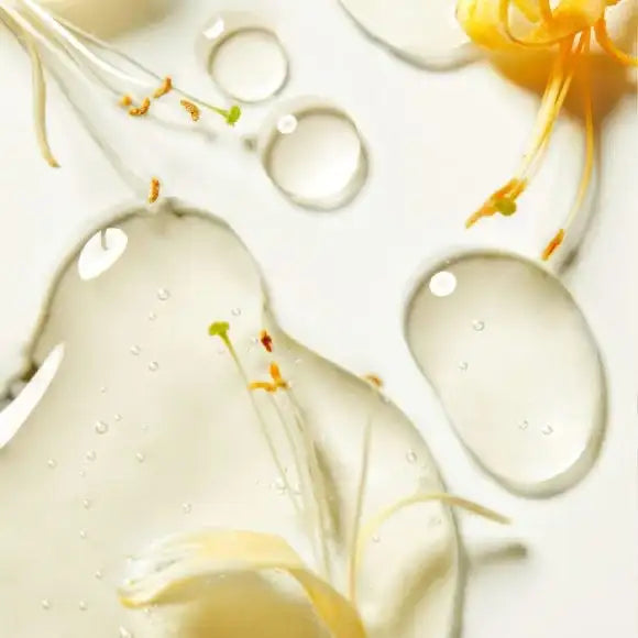 Clear, viscous liquid with delicate yellow flower petals and stems floating within it.