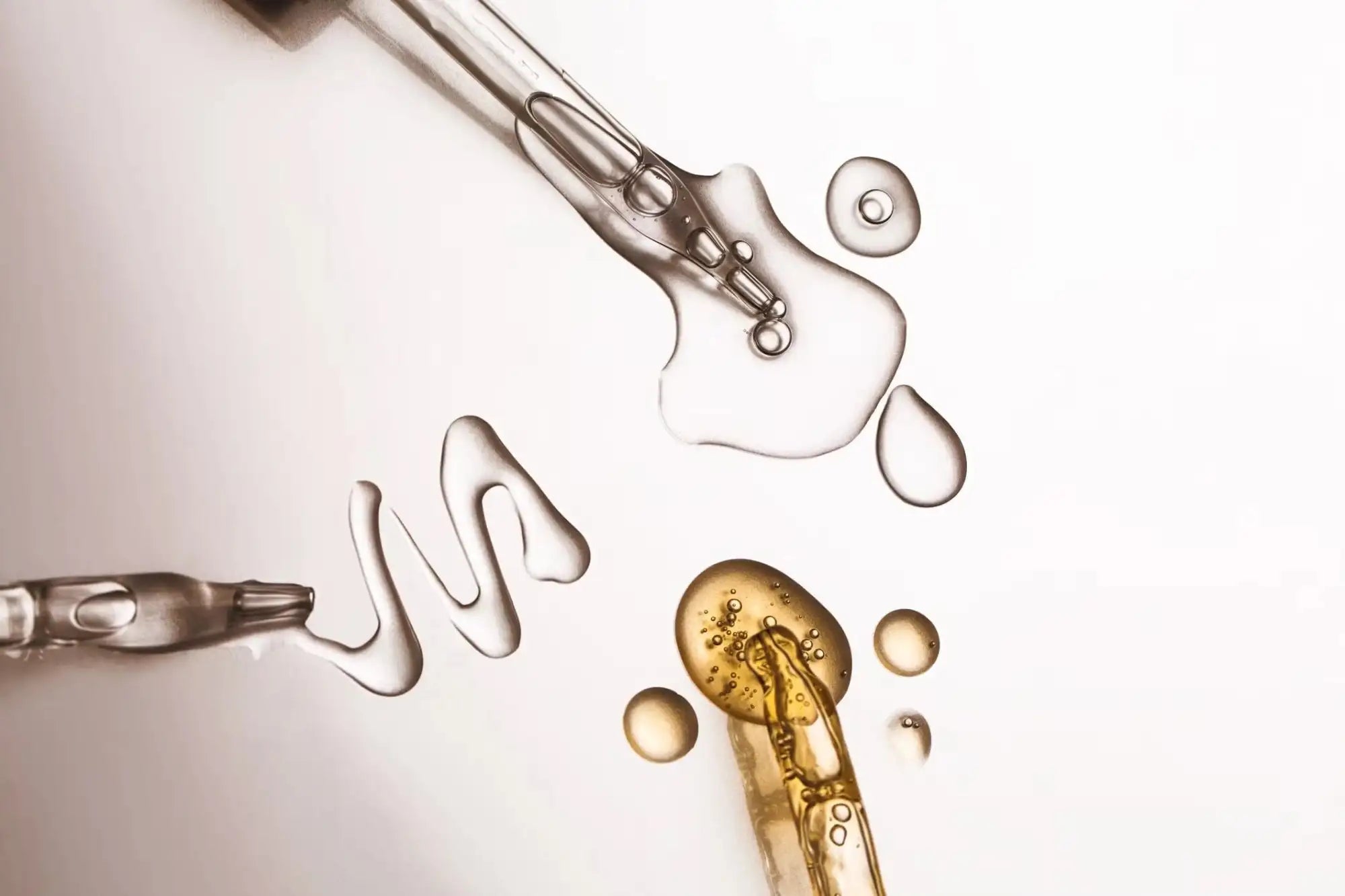 Glass dropper bottles with clear and golden liquid contents.
